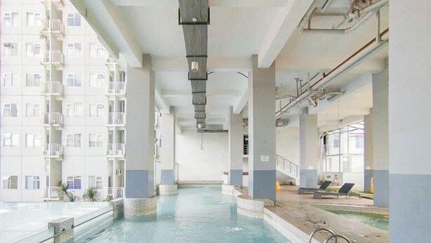 An indoor swimming pool with clear water, surrounded by a high-rise building with balconies.