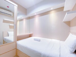 Habitación de hotel con cama, espejo, aire acondicionado de pared y lámpara.