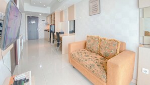 A modern living room with a sofa, a TV, and a kitchen area in the background.
