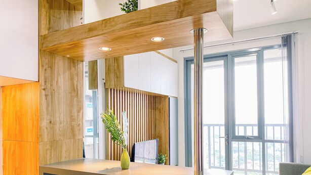 A modern kitchen with a central island, two white chairs, a grey sofa with a yellow pillow, and large windows with a balcony. - Cozy and Spacious 2BR Apartment at Royal Olive Residence (Jakarta)