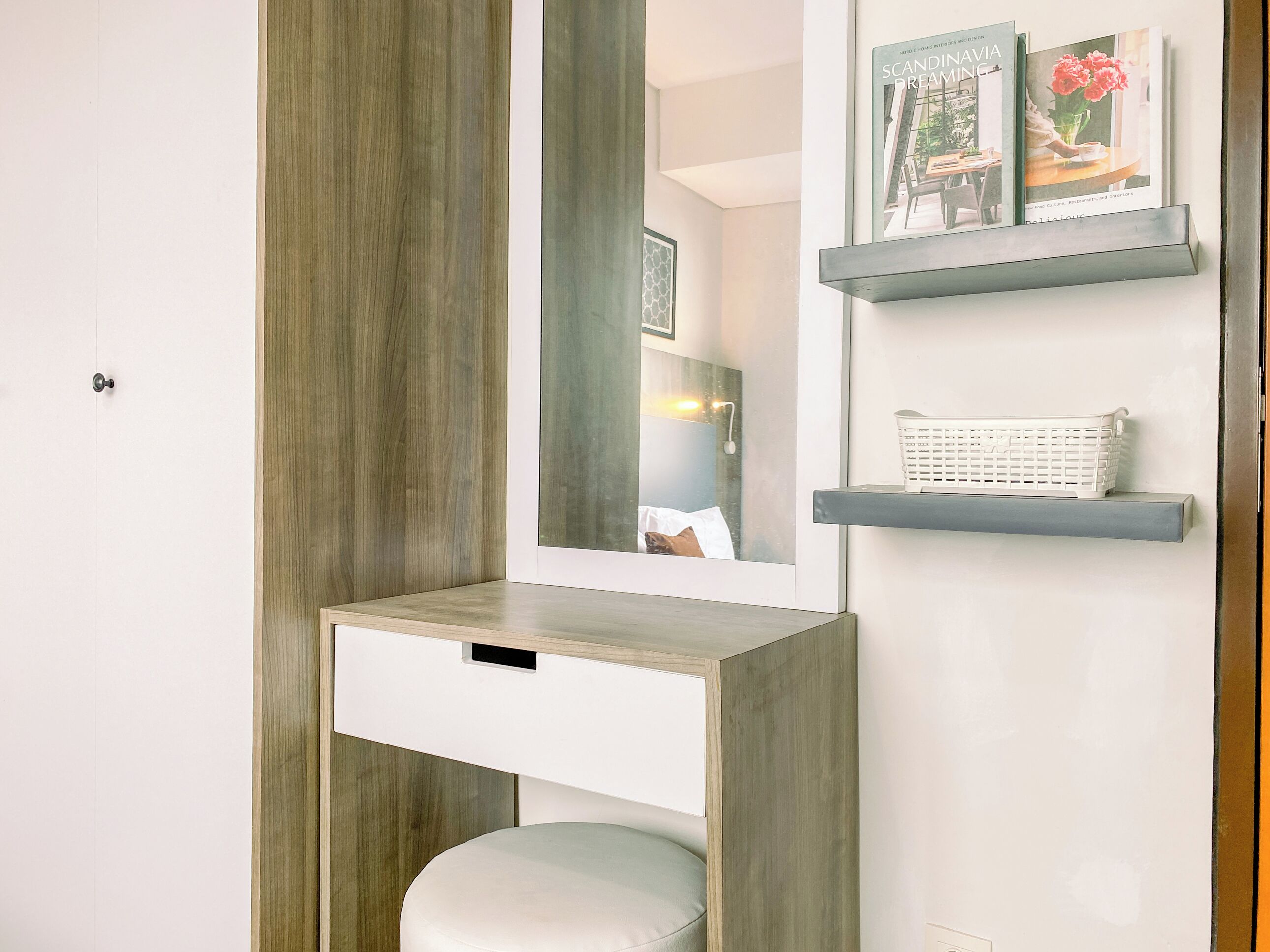 A modern bathroom with a built-in vanity, a mirror, and two floating shelves with decorative items.