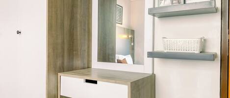 A modern bathroom with a built-in vanity, a mirror, and two floating shelves with decorative items.