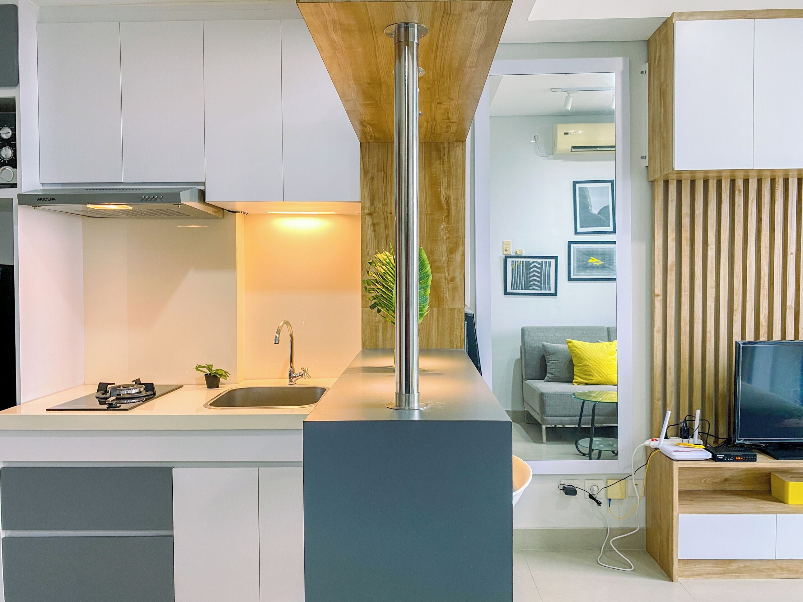 A modern kitchen with white cabinets, a stainless steel sink, and a wooden accent wall.