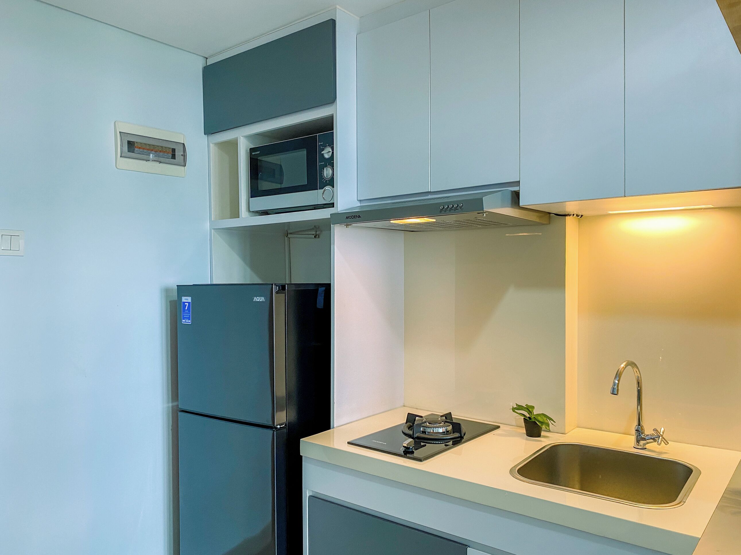 A compact kitchen with a built-in microwave, a stainless steel refrigerator, a gas stove, and a sink.