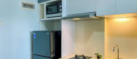 A compact kitchen with a built-in microwave, a stainless steel refrigerator, a gas stove, and a sink.