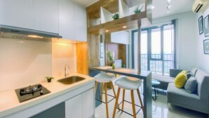 A modern kitchen with white cabinets, a built-in stove, and a bar area with stools. - Cozy and Spacious 2BR Apartment at Royal Olive Residence (Jakarta)