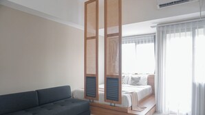 A modern bedroom with a sofa, a bed with a wooden headboard, and a window with curtains.