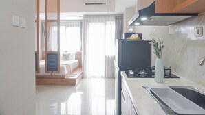 A modern kitchen with a stove, sink, and a vase with flowers. There is a bed with a wooden headboard and a window with curtains.