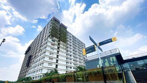 A multi-story hotel with a modern design, featuring a prominent entrance and a sign indicating nearby locations.