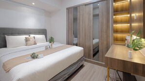 Une chambre à coucher moderne avec un grand lit, une armoire en bois dotée d’étagères éclairées et un petit espace bureau.