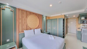 A modern hotel room with a bed, a vanity, a mirror, a round wall decoration, and a kitchenette.