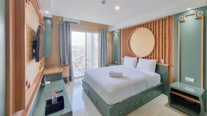 A hotel room with a bed, a desk with a chair, a TV, and a view of the outside.