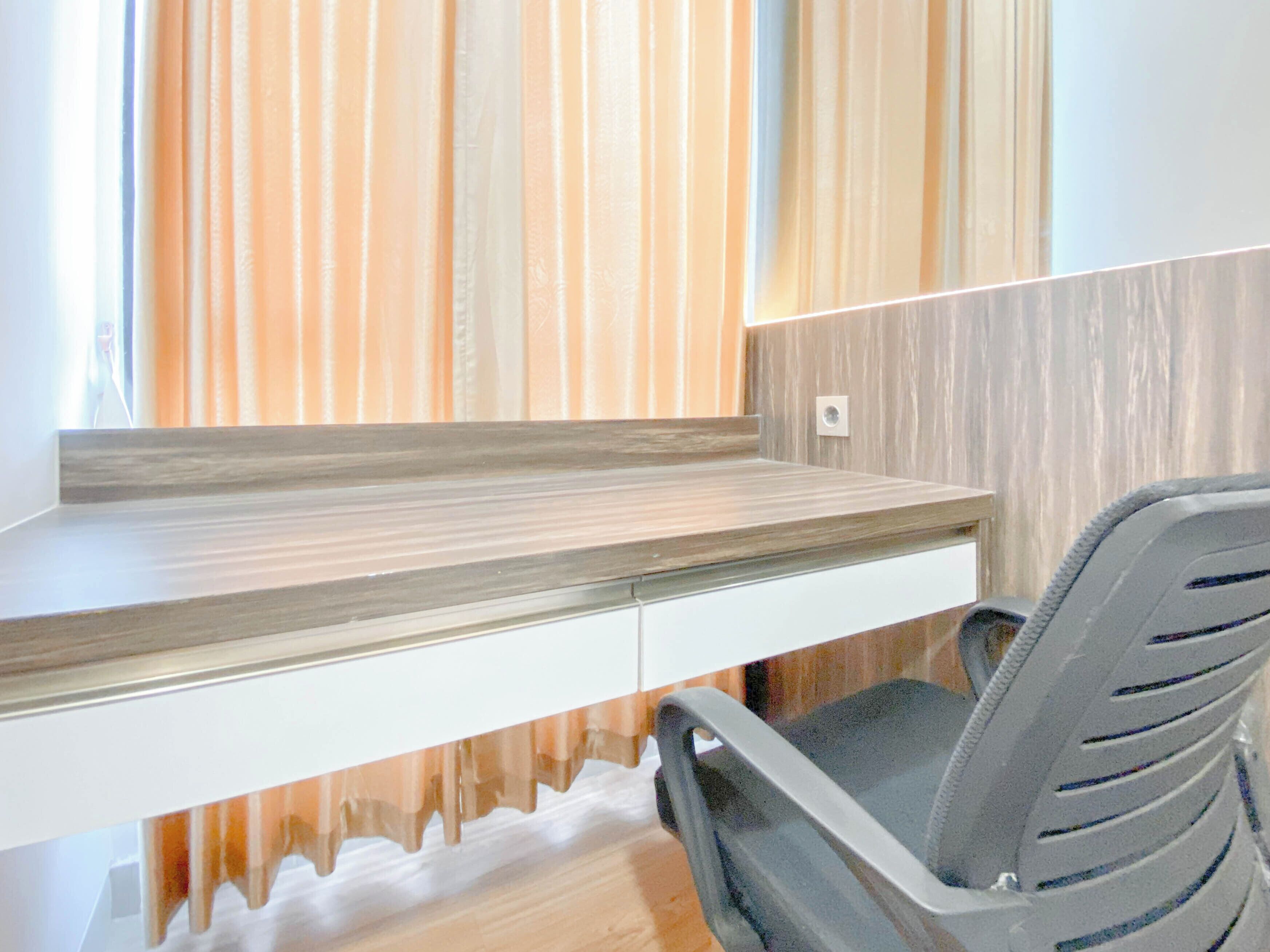 A modern office desk with a built-in shelf, a chair, and a wall with vertical wooden slats.