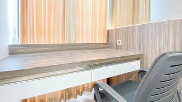 A modern office desk with a built-in shelf, a chair, and a wall with vertical wooden slats.