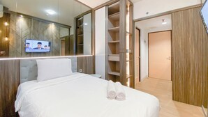 Hotellihuone, jossa on suuri sänky, seinälle asennettu televisio ja peilillä varustettu vaatekaappi.