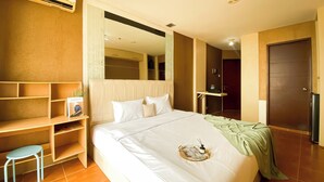 Ein Hotelzimmer mit Bett, Nachttisch, Stuhl, Kleiderschrank und einer Tür.