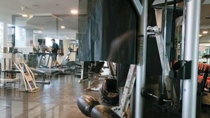 Ein Fitnessstudio mit Laufbändern, Kraftgeräten und einer Spiegelwand.