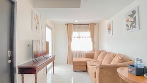 A living room with a beige sofa, a wooden coffee table, and a TV on a stand. - The Spacious 2BR at Grand Asia Afrika Apartment (Bandung)