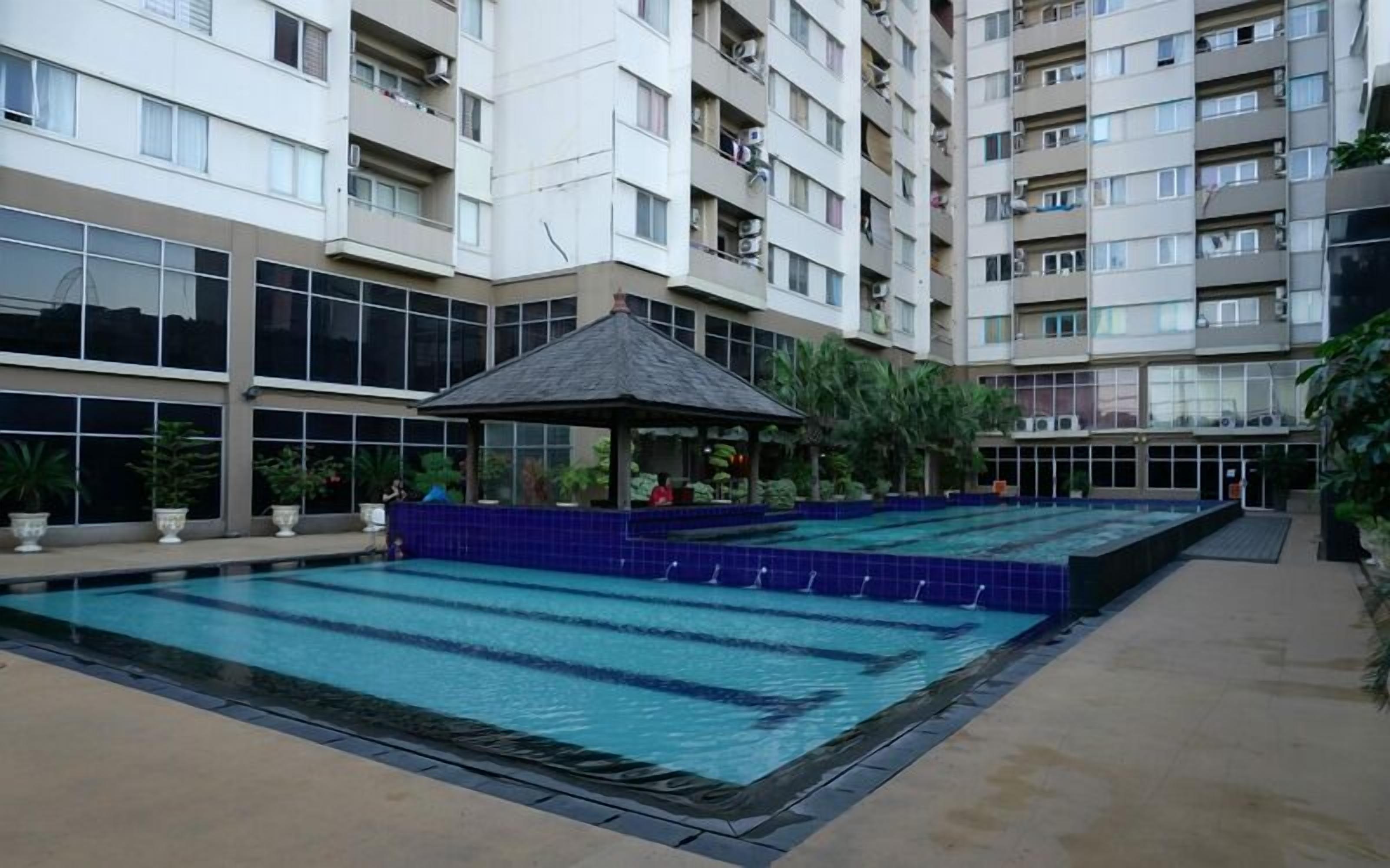 A swimming pool area with a gazebo, surrounded by a multi-story residential building.