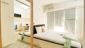 A modern hotel room with a bed, a desk, a chair, and a TV. - Comfortable and Simply 1BR Apartment Centro City (Jakarta)