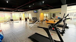 A gym with cardio equipment, weight machines, and a TV screen. - Comfortable and Simply 1BR Apartment Centro City (Jakarta)