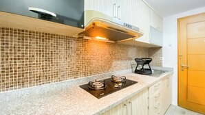 A kitchen with a gas stove, a microwave, and a coffee maker on the counter. - Comfortable and Simply 1BR Apartment Centro City (Jakarta)