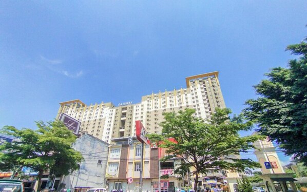 A multi-story residential building with balconies, a visible entrance, and a clear sky. - The Serene Sanctuary 2BR at Gateway Ahmad Yani Cicadas Apartment (Bandung)