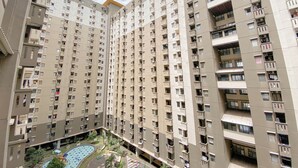 A high-rise residential building with multiple balconies, a rooftop pool, and a landscaped courtyard.