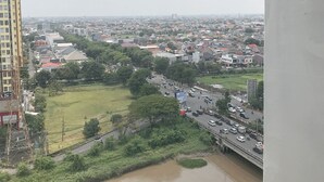 A cityscape with a river, buildings, and a bridge. - Modern Studio at Bale Hinggil Apartment (Surabaya)