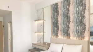 A modern hotel room with a large bed, a bedside table, a nightstand, and a wall-mounted artwork. - Modern Studio at Bale Hinggil Apartment (Surabaya)