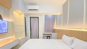 Ein Hotelzimmer mit einem Bett, einem Schreibtisch, einem Fernseher und einer Klimaanlage.