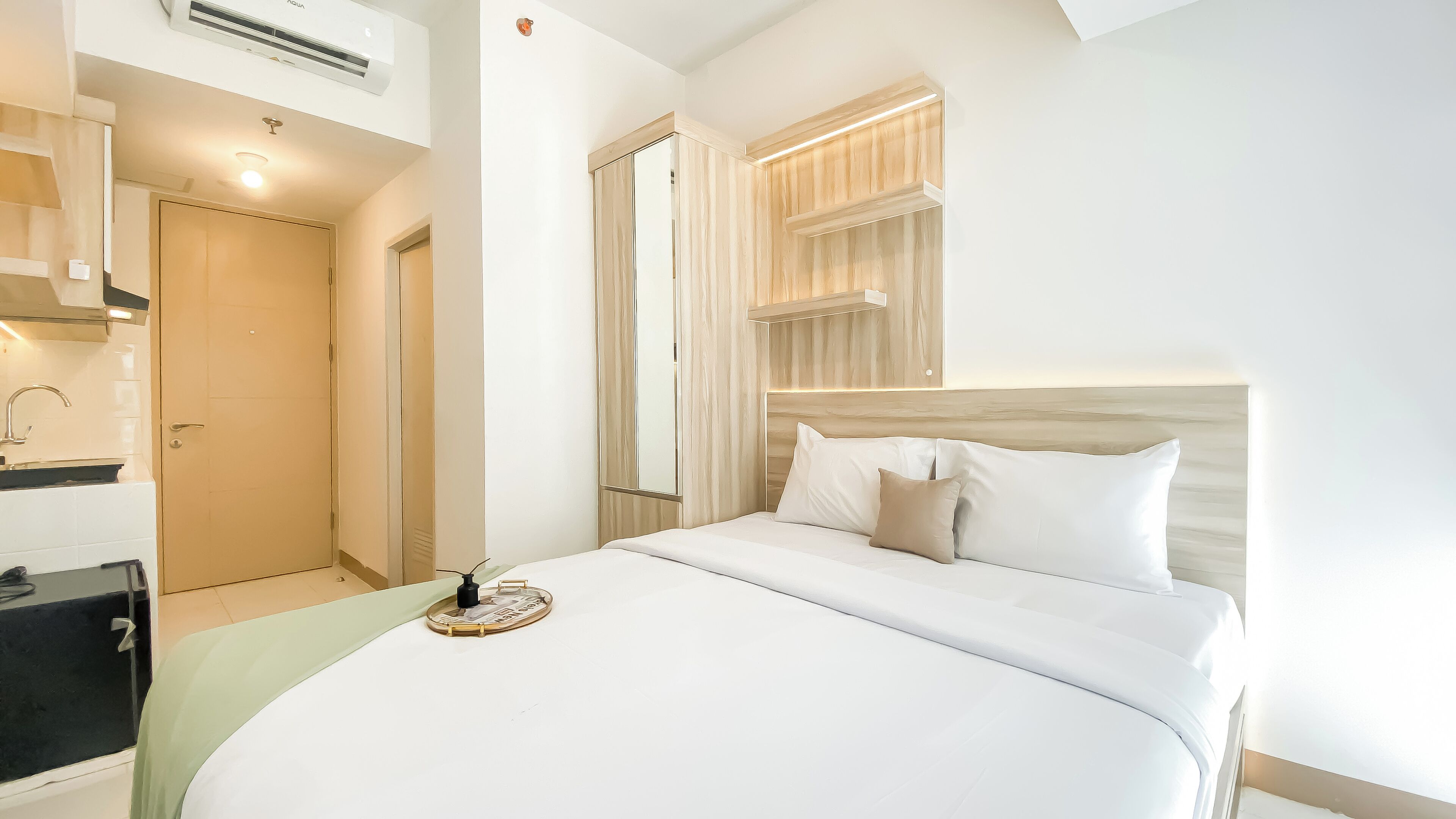 A hotel room with a bed, a bedside table, a mirror, and a window with curtains.