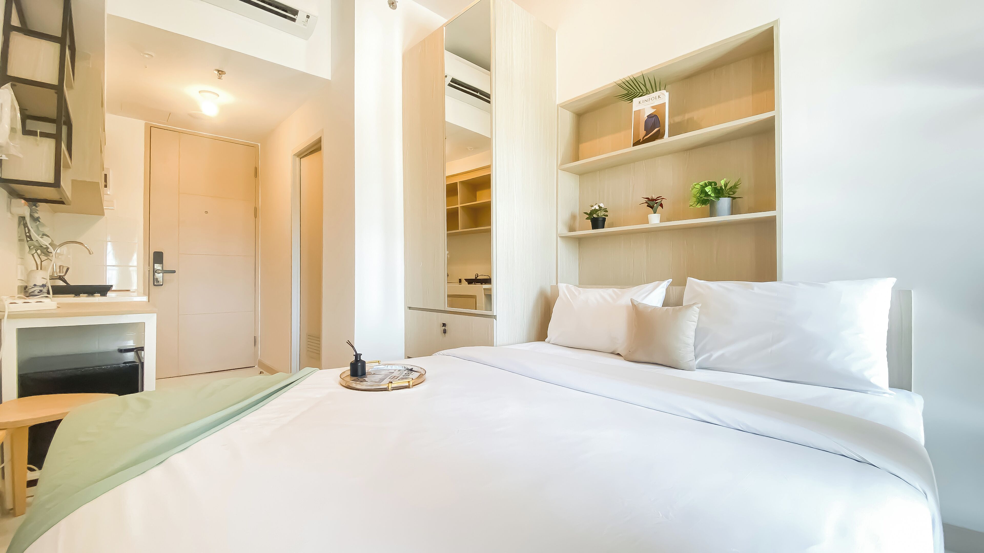 Une chambre d’hôtel moderne dotée d’un grand lit, d’un bureau avec une chaise et d’étagères intégrées ornées d’objets décoratifs.