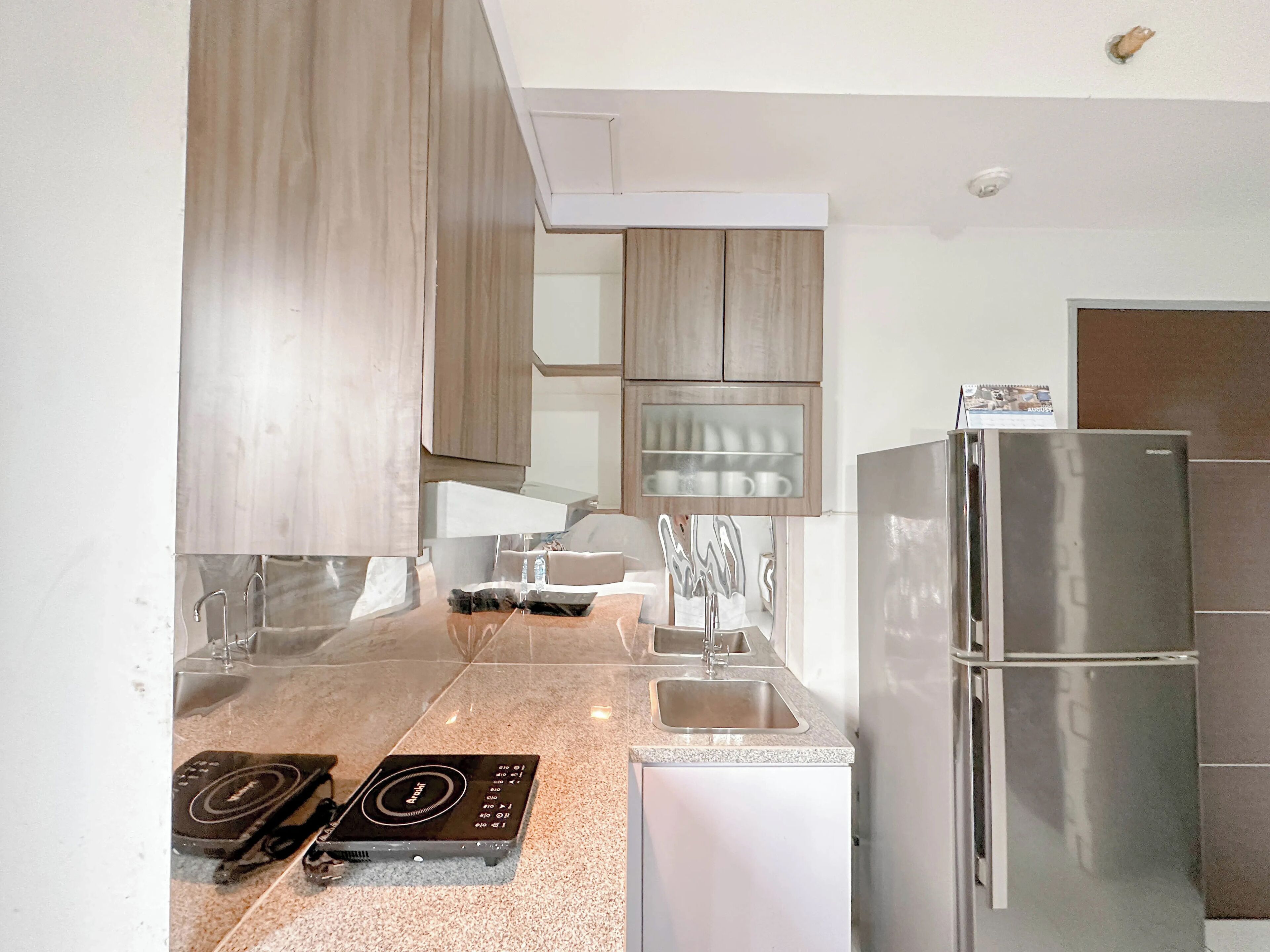 Una cocina moderna con un refrigerador de acero inoxidable, lavamanos doble y horno empotrado.