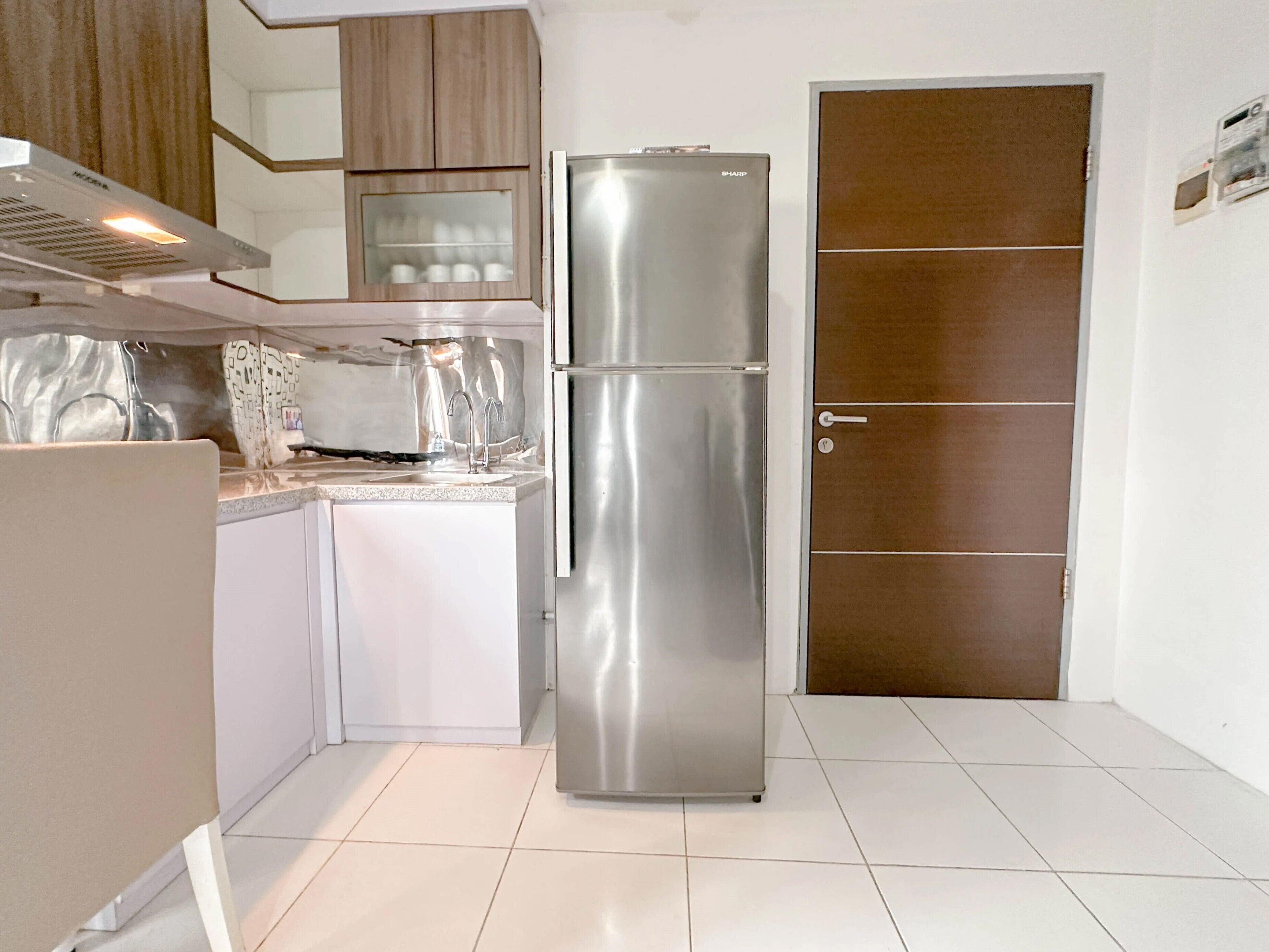 A compact kitchen with a stainless steel refrigerator, a built-in oven, and a microwave.