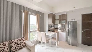 Une cuisine moderne avec un coin repas, comprenant une table blanche, des chaises et un canapé agrémenté de coussins à motifs.
