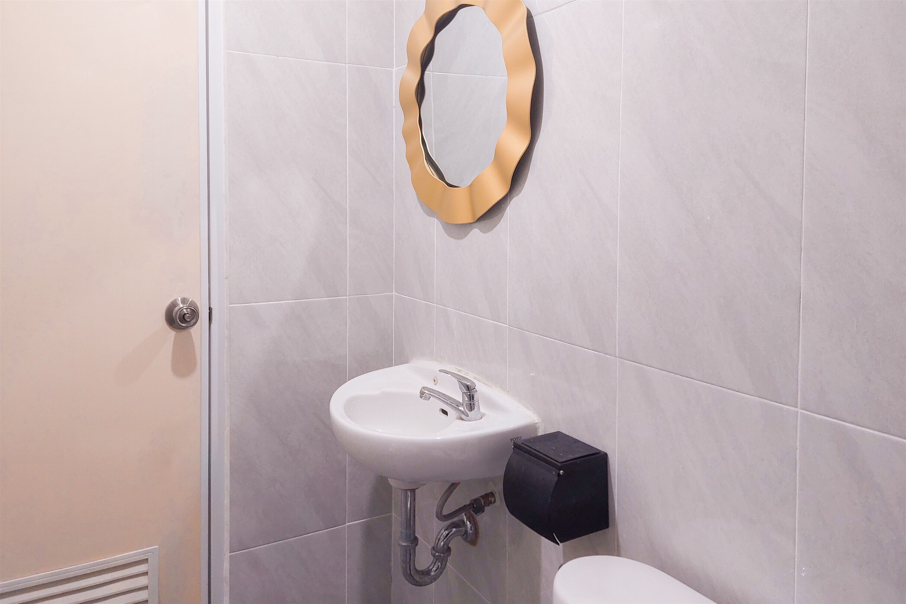 Une salle de bain avec un lavabo blanc, un miroir et un distributeur de savon noir.