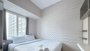 Habitación de hotel con una cama grande, una ventana con cortinas, un escritorio integrado y vistas a edificios altos.