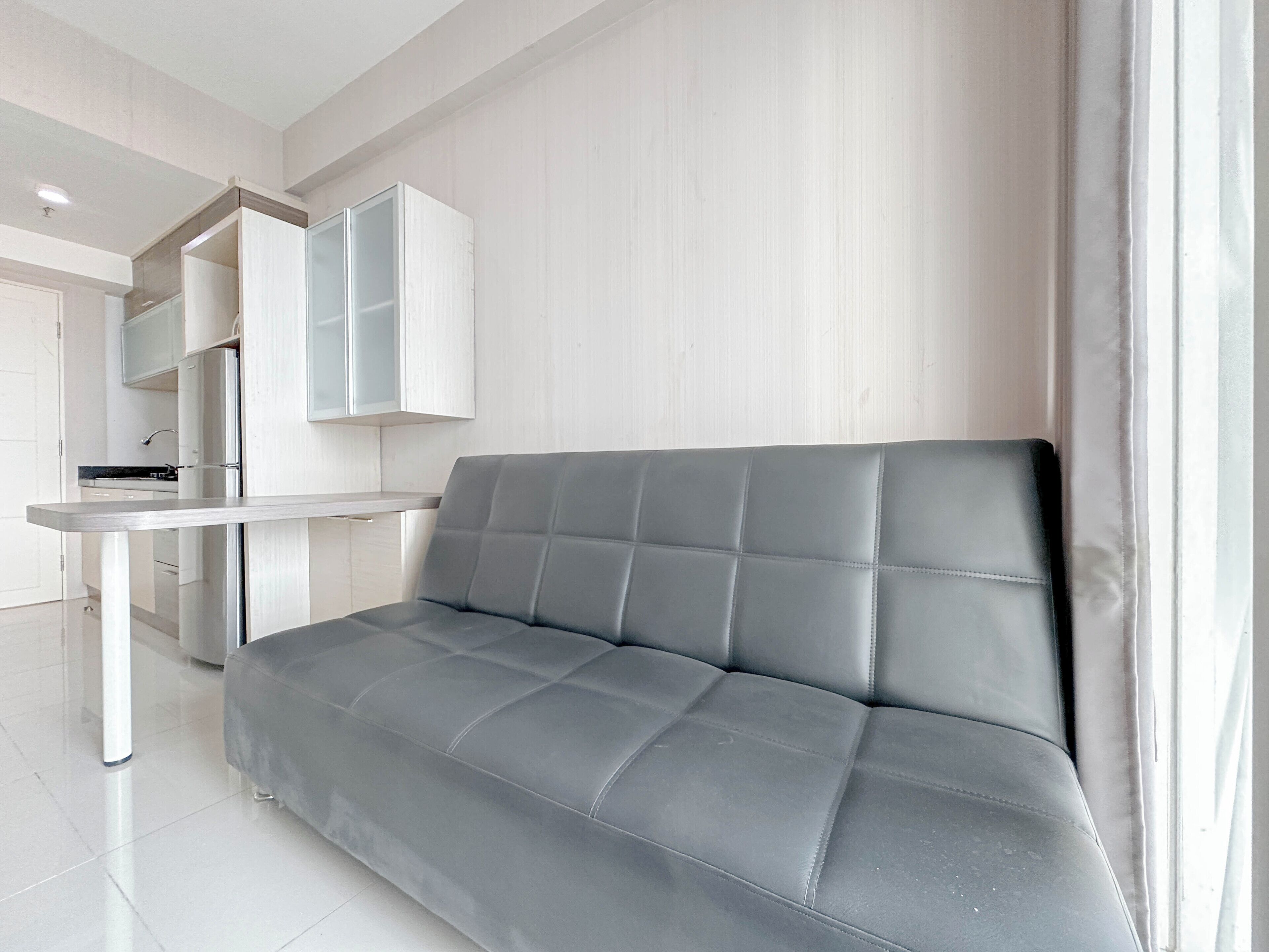 Un salon moderne avec un canapé gris, un meuble blanc et une petite table.