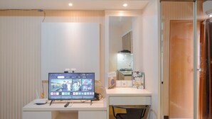 Una habitación moderna con escritorio, televisor de pantalla plana, silla y espejo.