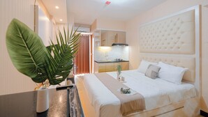 Una habitación de hotel con una cama grande, una kitchenette pequeña y una planta en maceta.