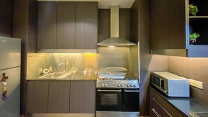 A modern kitchen with a stainless steel refrigerator, a built-in oven, a microwave, and a range hood. - Spacious and Cozy 2BR Apartment Kemang Village (Jakarta)