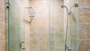A glass-enclosed shower stall with a handheld showerhead, a handheld showerhead, and a glass shelf. - Spacious and Cozy 2BR Apartment Kemang Village (Jakarta)