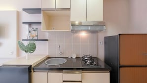 A compact kitchen with a gas stove, sink, and a refrigerator. - Good Deal and Comfy Studio Apartment at Cinere Bellevue Suites (Depok)