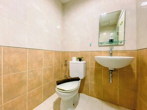 A bathroom with a toilet, sink, and mirror. - Strategic and Homey Studio at Tamansari Sudirman Apartment (Jakarta)