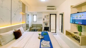 Ein modernes Hotelzimmer mit einem großen Bett, einem an der Wand befestigten Fernseher und einem Schreibtisch mit Pflanze.