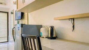 Eine Küche mit Kühlschrank, Mikrowelle, Wasserkocher und Kaffeemaschine auf der Arbeitsplatte.