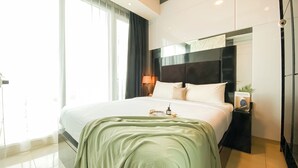 Moderni hotellihuone, jossa on suuri sänky, yöpöytä, lamppu ja näkymä ulos.
