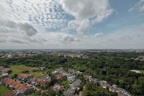 An aerial view of a residential area with houses, green spaces, and a distant city skyline. - Good Deal 2BR Apartment Cinere Bellevue Suites (Depok)