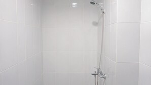 Een douche met een handdouche en een kraan op de muur.